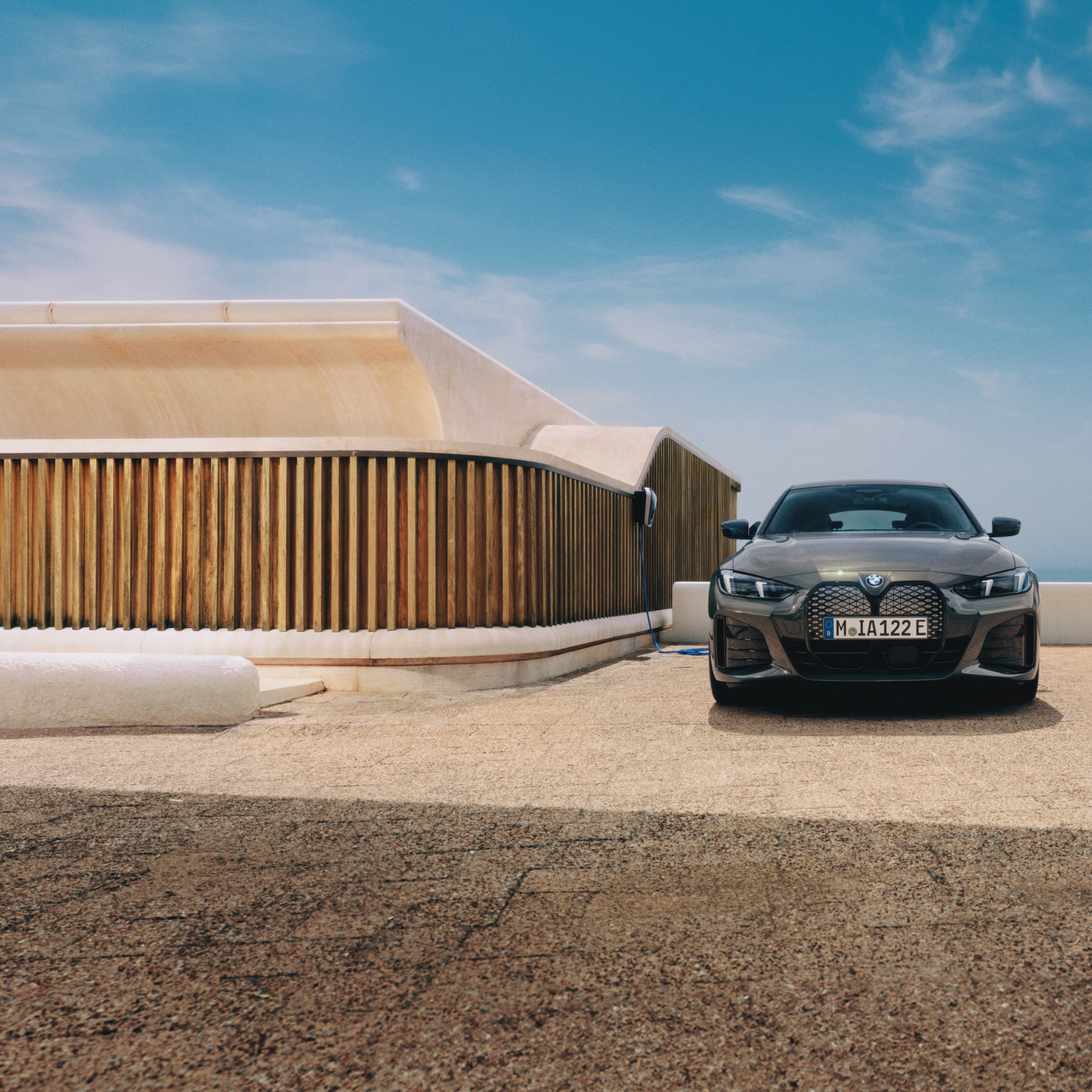 Мъж със смартфон стои до BMW i4, което е свързано с Wallbox