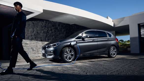 Plug-in хибрид BMW 225xe Актив Турър F45 три четвърти изглед отстрани пред сграда Plug-in хибрид BMW 225xe Актив Турър F45 три четвърти изглед отстрани пред сграда с модел