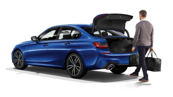 BMW Серия 3 Седан, автоматично управление на багажника. Три четвърти заден кадър на BMW Серия 3 Седан с водач, който автоматично отваря вратата с целенасочено движение с крак.
