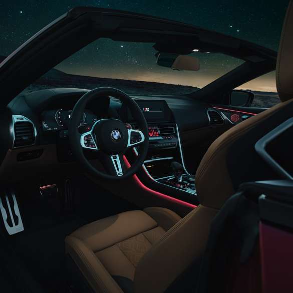 BMW M8 Competition Кабриолет, кокпит BMW M8 Competition Кабриолет, кокпит през нощта с М кожен волан и червено вътрешно осветление.