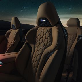 М Спортни седалки с кожена тапицерия 'Merino'. BMW M8 Competition Кабриолет с отворен мек покрив под звездно небе, интериор с М Спортни седалки с кожена тапицерия 'Merino' и червено вътрешно осветление.