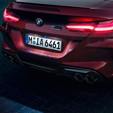 BMW M8 Competition Кабриолет, снимка отблизо на задната част. BMW M8 Competition Кабриолет в цвят Motegi Red metallic, снимка отблизо на задната част с LED задни светлини и емблема M8 Competiton.