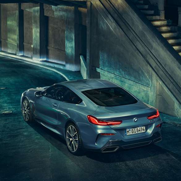 BMW M850i xDrive Купе, три четвърти изглед отзад отляво. BMW M850i xDrive Купе в Barcelona Blue metallic, три четвърти изглед отзад отляво в покой през нощта.