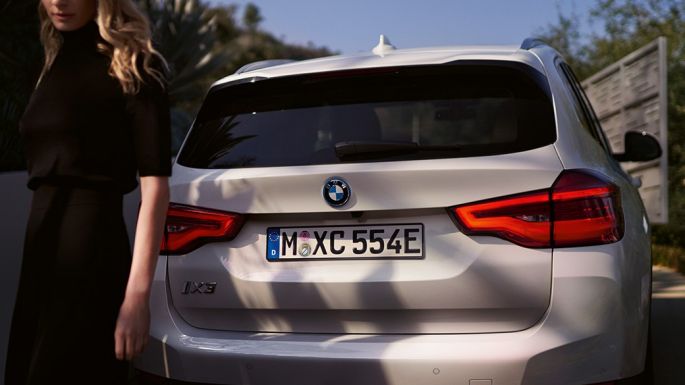 Задна част със специфичен за BMW i дифузор BMW iX3 G08 изглед отзад с жена Задна част със специфичен за BMW i дифузор BMW iX3 G08 2020 Mineral White metallic изглед отзад с жена