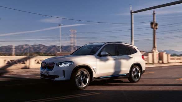 Адаптивно M окачване BMW iX3 G08 в движение по пътя Адаптивно M окачване BMW iX3 G08 2020 Mineral White metallic три четвърти изглед отпред в движение по пътя
