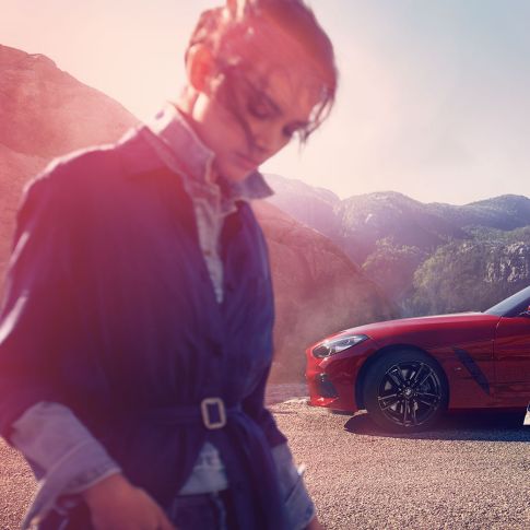 BMW Z4 Роудстър на фона на планински пейзаж Мъж и жена пред BMW Z4 Роудстър на фона на планински пейзаж