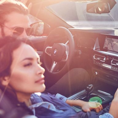 BMW Z4 Роудстър с мъж и жена Тъмнокоса жена и мъж в BMW Z4 Роудстър