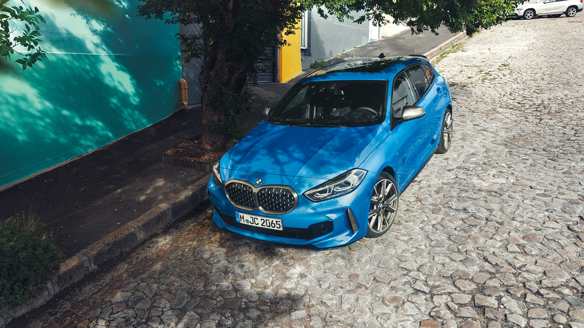 BMW Серия 1, паркирано на улицата BMW Серия 1 в цвят Misano Blue metallic, три четвърти изглед отпред, паркирано на улицата, от перспектива птичи поглед.