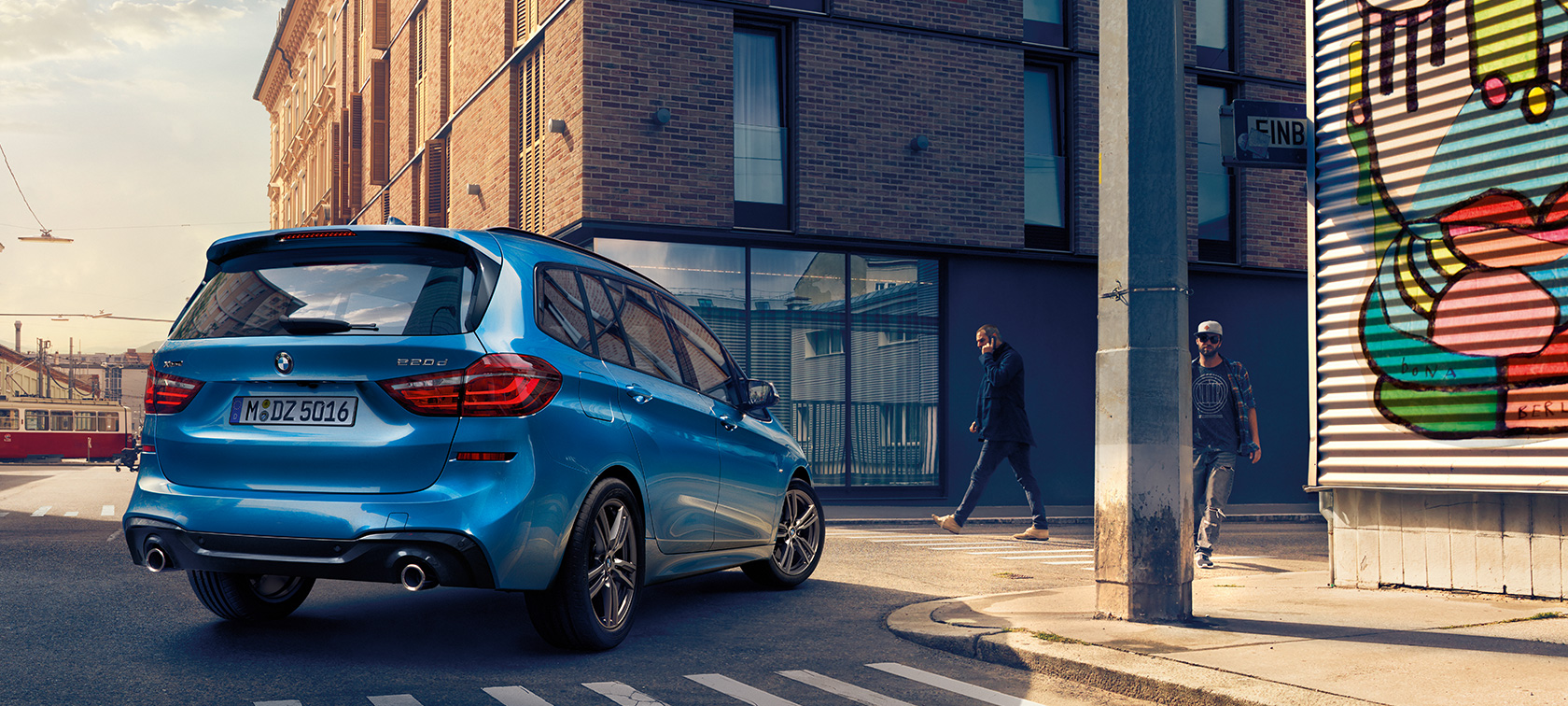 Мъж до BMW Серия 2 Гран Турър F46 фейслифт 2018 Estoril Blue metallic от перспектива птичи поглед, паркирано на пътя