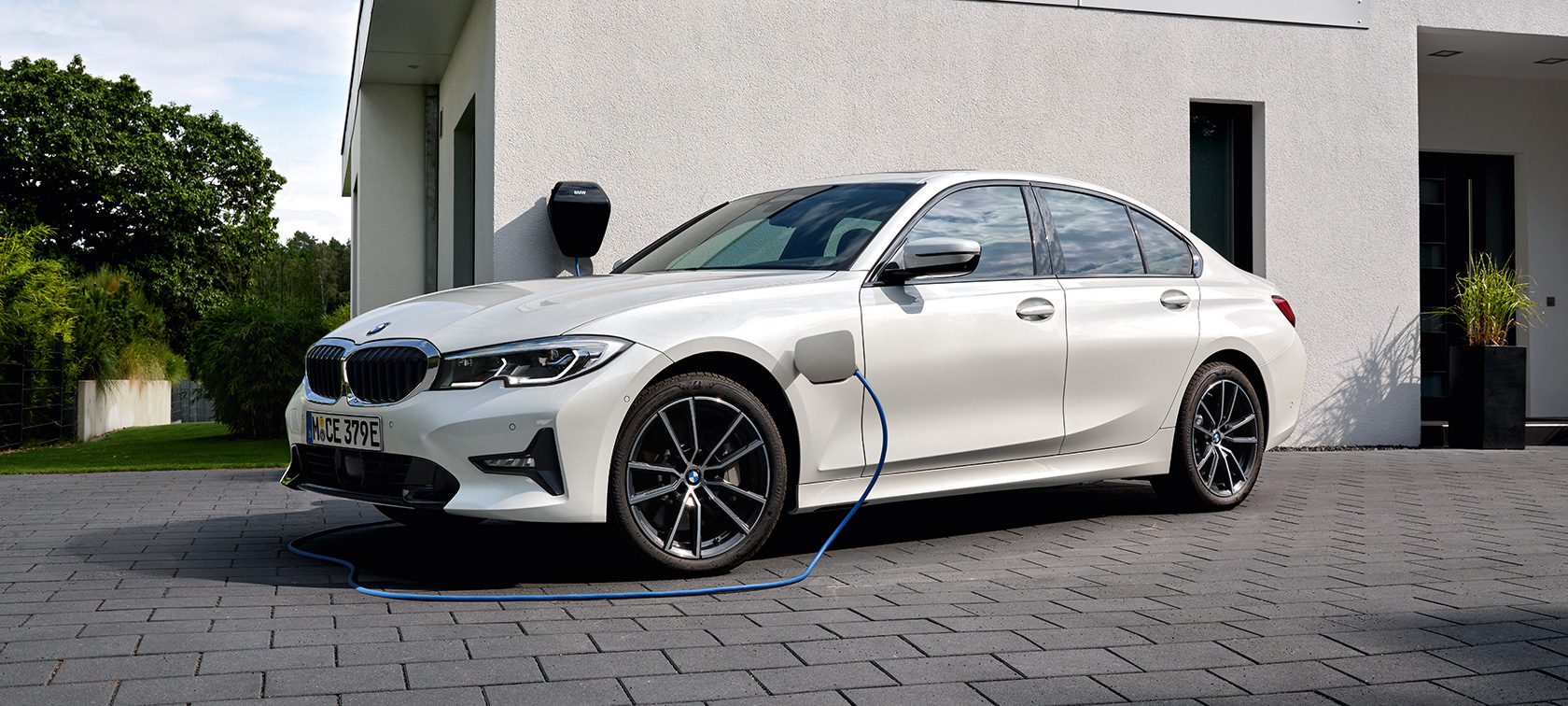 Plug-in хибрид BMW Серия 3 Седан 2021 G20 G20 три четвърти изглед отстрани при зареждане Plug-in хибрид BMW Серия 3 Седан 2021 G20 три четвърти изглед отстрани при зареждане пред гараж