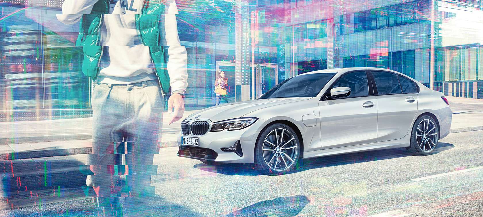 BMW Серия 3 Седан, изглед отстрани BMW 330e. Страничен изглед на BMW 330e Седан покой пред стъклени сгради със пешеходци.