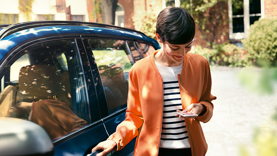 BMW Service жена със смартфон до вратата на своето BMW BMW Service жена със смартфон до вратата на своето BMW