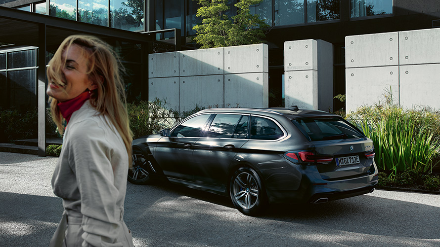 Жена BMW Серия 5 Туринг G31 фейслифт 2020 Sophisto Grey Brilliant Effect metallic 7/8 изглед отстрани Жена пред паркирано BMW Серия 5 Туринг G31 фейслифт 2020 Sophisto Grey Brilliant Effect metallic 7/8 изглед отстрани