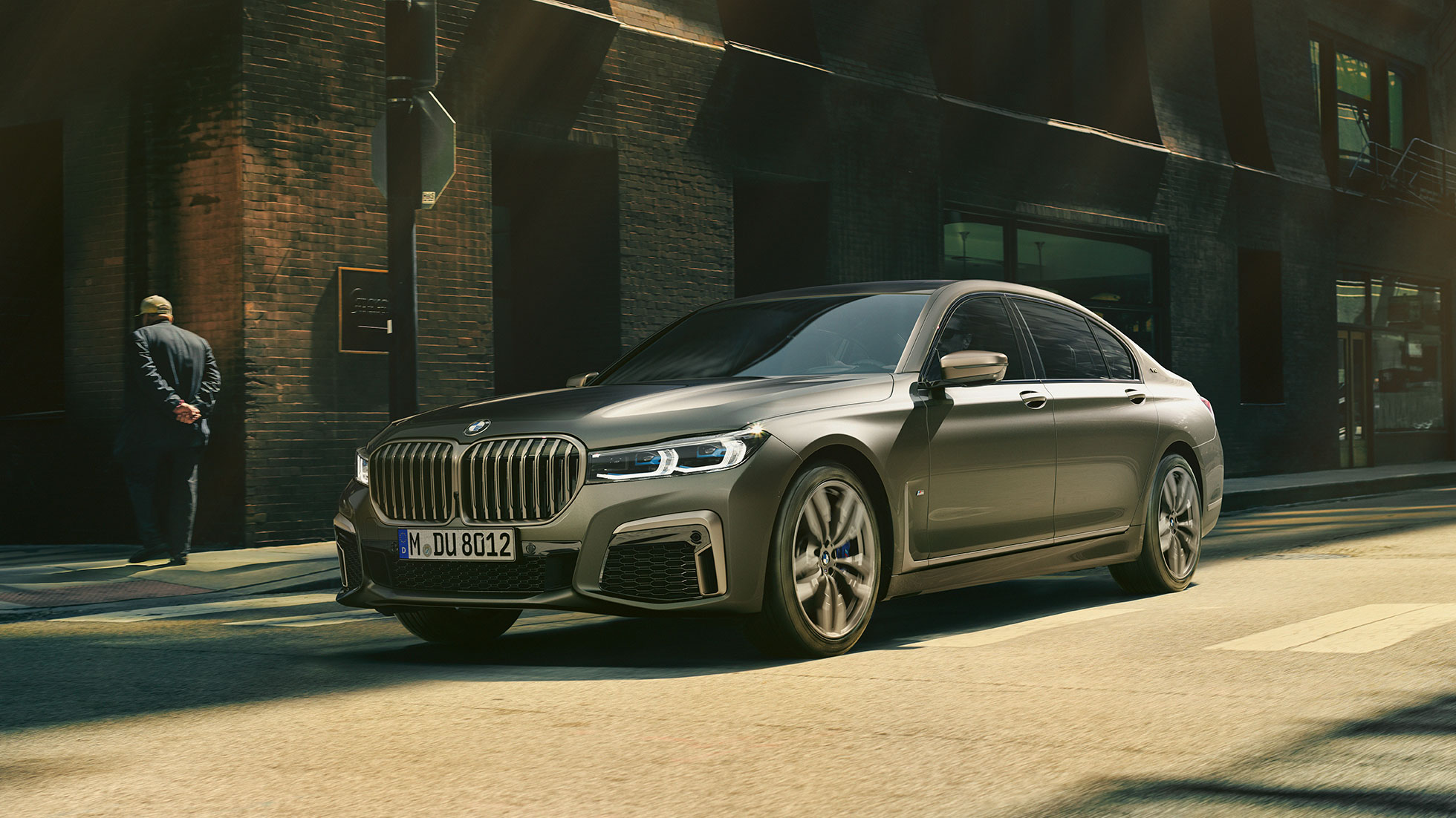 BMW M760Li xDrive на фона на града BMW M760Li xDrive, сранична снимка отпред се движи по улица на фона на града