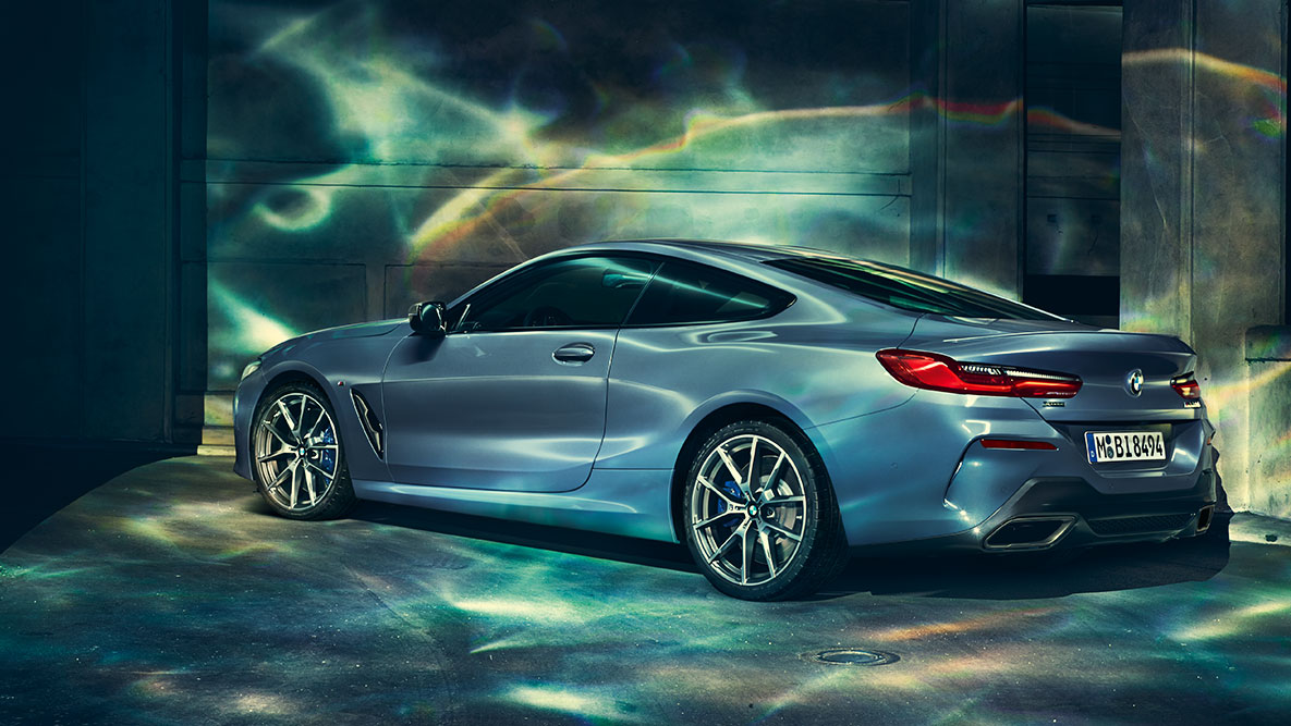 BMW Серия 8 Купе, три четвърти снимка отзад. Три четвърти снимка отзад на BMW Серия 8 Купе през нощта на фона на града.