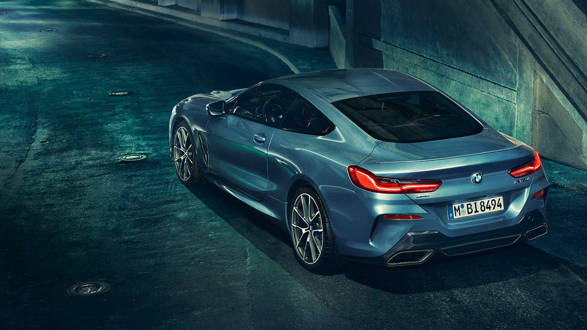 BMW Серия 8 Купе, три четвърти снимка отзад. Три четвърти снимка отзад на BMW Серия 8 Купе през нощта на фона на града.