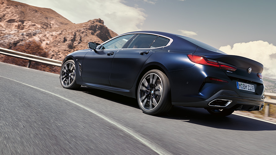 BMW 840i xDrive Гран Купе M Спортен пакет G16 LCI Facelift 2022 в движение по планински път BMW 840i xDrive Гран Купе М Спортен пакет G16 LCI Facelift 2022 BMW Individual Frozen Tansanite Blue metallic три четвърти изглед отзад в движение по планински път
