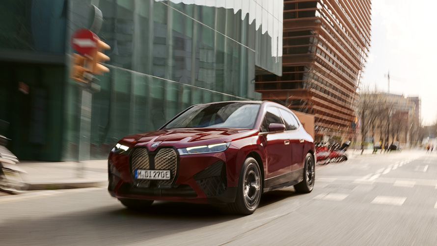 BMW iX i20 електрически SUV BMW iX xDrive50 асистиращи системи BMW iX i20 2021 електрически SUV BMW iX xDrive50 Aventurine Red в движение в градска среда
