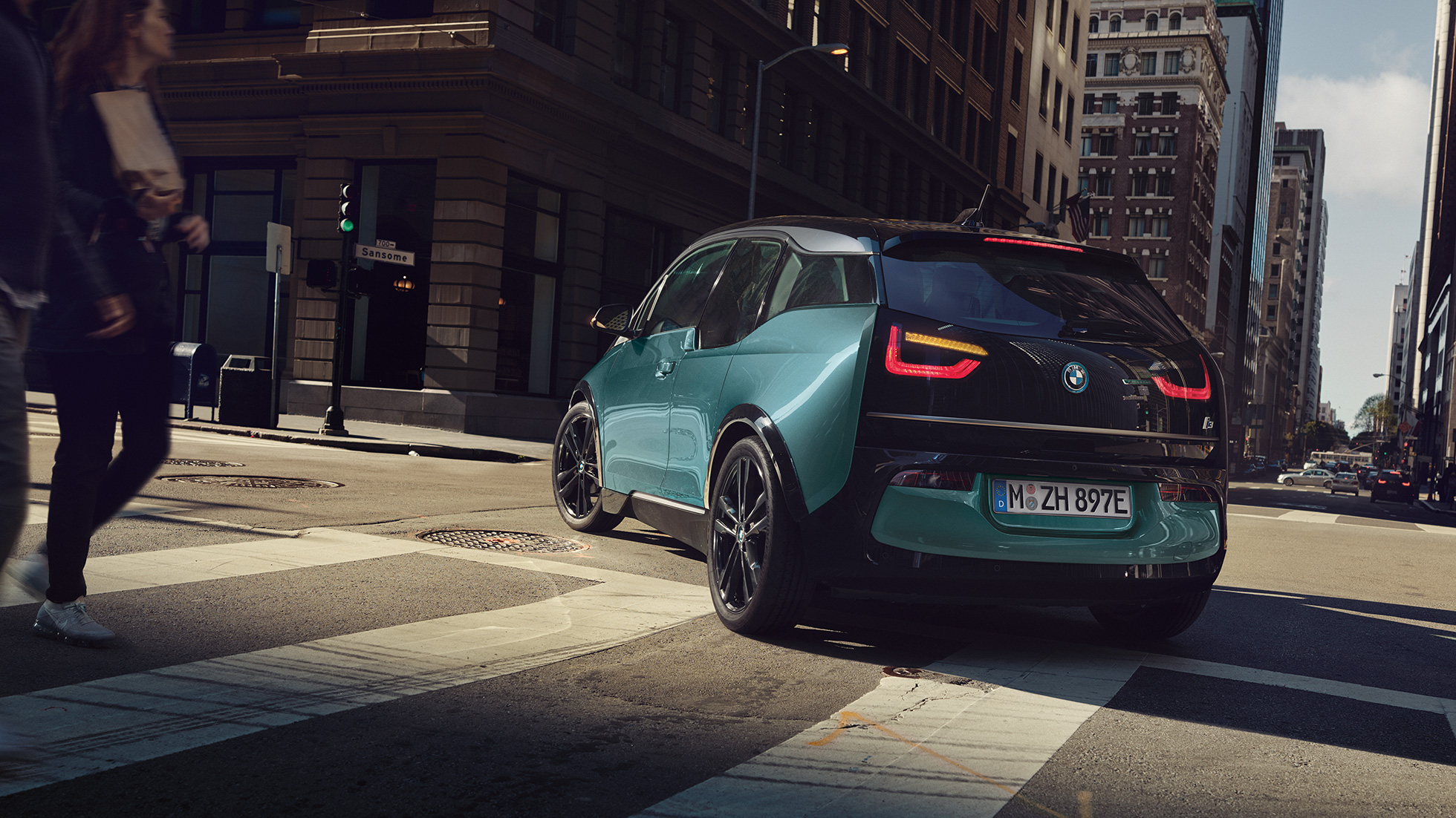 BMW i3 2018 три четвърти изглед отзад, в движение BMW i3 I01 2018 Jucaro Beige с акцент Frozen Grey metallic три четвърти изглед отзад, в движение на фона на града
