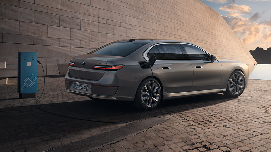 BMW i7 G70 3/4 изглед отзад BMW i7 G70 BMW Individual Oxid grey metallic 3/4 изглед отзад в покой пред сграда
