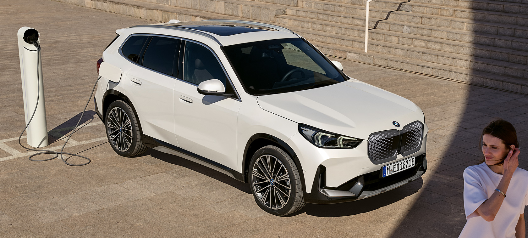 BMW iX1 U11 BEV 2022 изглед отстрани при зареждане BMW iX1 U11 BEV 2022 Mineral White metallic 2/3 изглед отстрани при зареждане