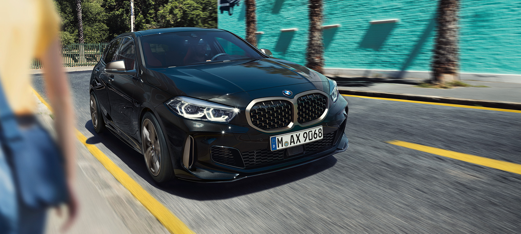 BMW M135i xDrive, три четвърти изглед отпред. BMW M135i xDrive в Black Sapphire metallic, три четвърти изглед отпред в движение.