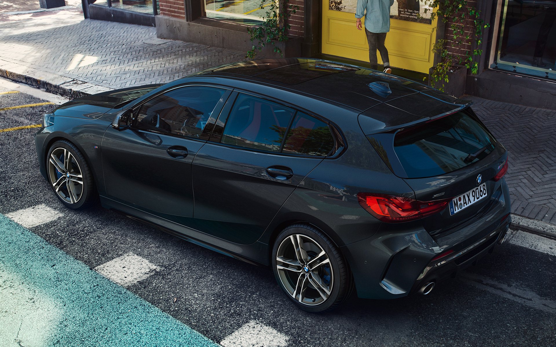 BMW M135i xDrive (F40) в Sapphire Black metallic паркирано, изглед отстрани от перспектива птичи поглед