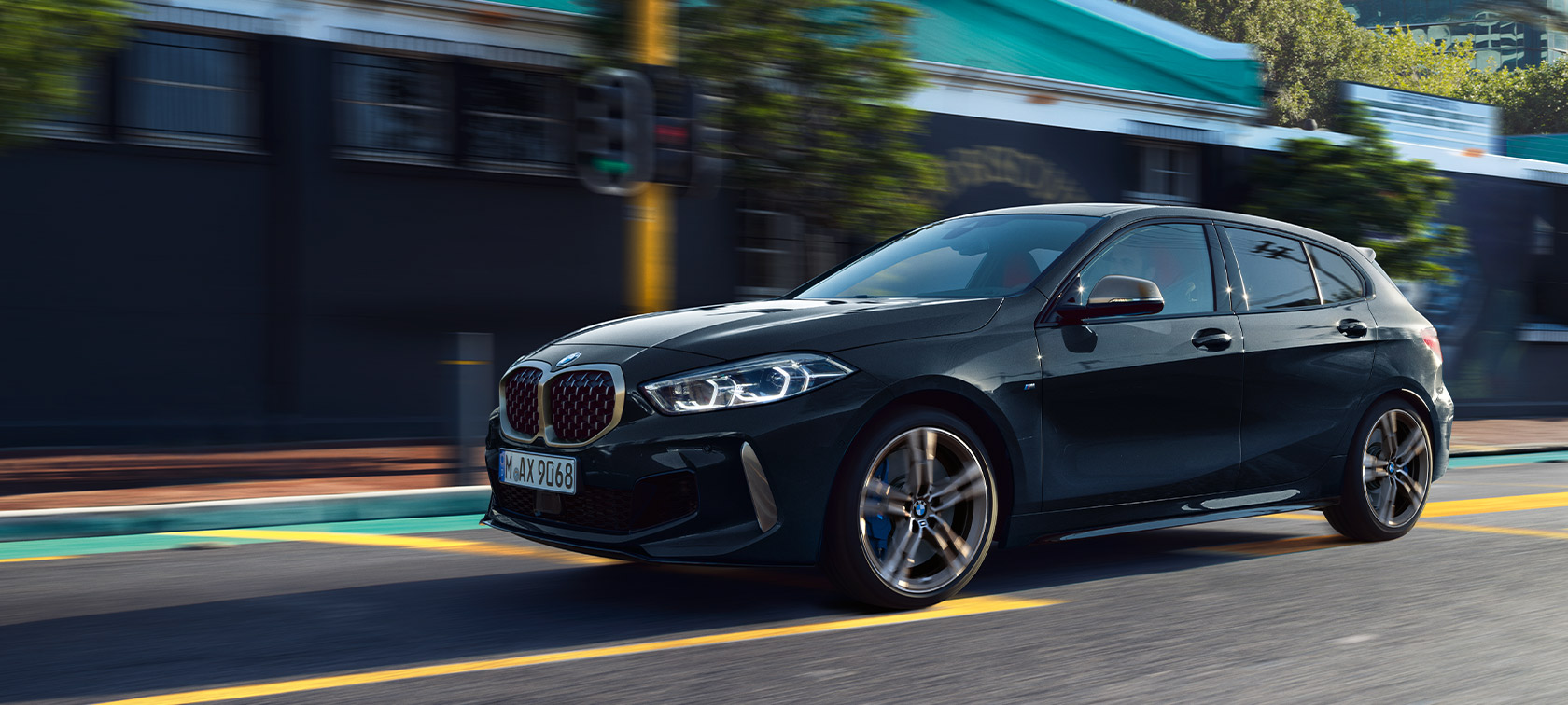 BMW 1er M135i xDrive (F40) в Sapphire Black metallic движещ се автомобил на фона на града