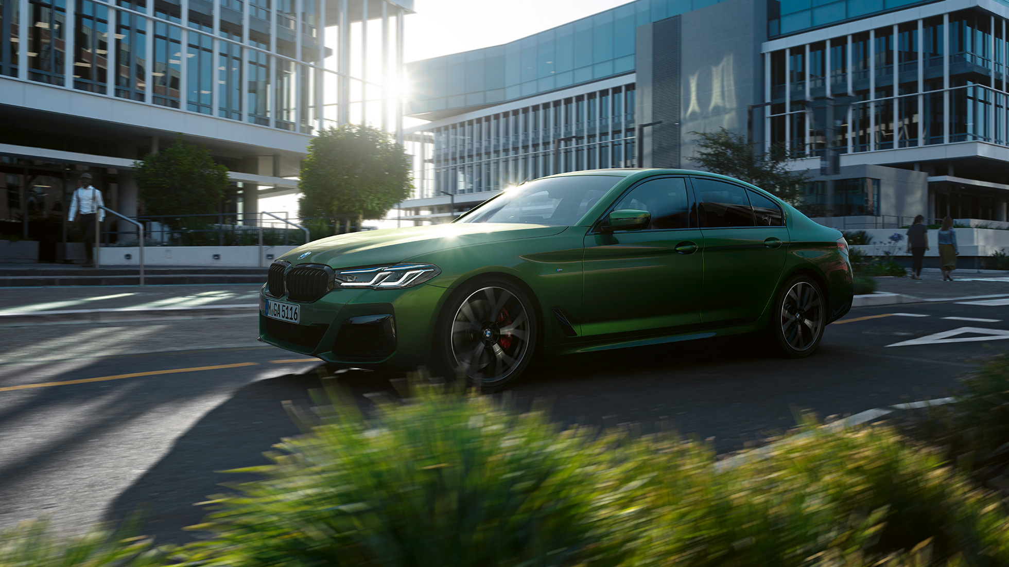 BMW M550i xDrive Седан G30 LCI Facelift 2020 изглед отстрани в движение BMW M550i xDrive Седан G30 LCI Facelift 2020 BMW Individual Verde Ermes metallic изглед отстрани в движение из града