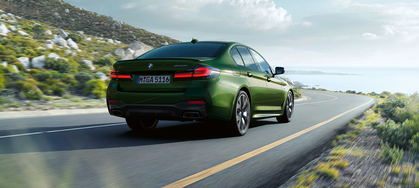 BMW M550i xDrive Седан G30 LCI Facelift 2020 три четвърти изглед отзад в движение BMW M550i xDrive Седан G30 LCI Facelift 2020 BMW Individual Verde Ermes metallic три четвърти изглед отзад в движение