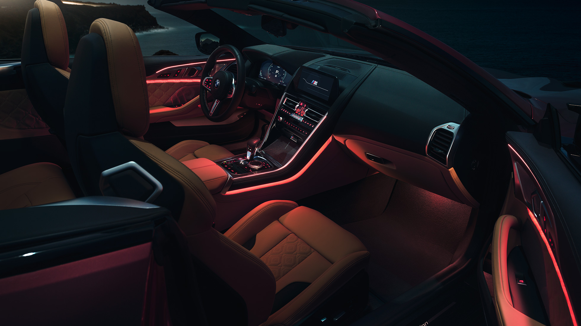BMW M8 Competition Кабриолет, интериор. BMW M8 Competition Кабриолет с отворен мек покрив, интериор с червено вътрешно осветление през нощта.