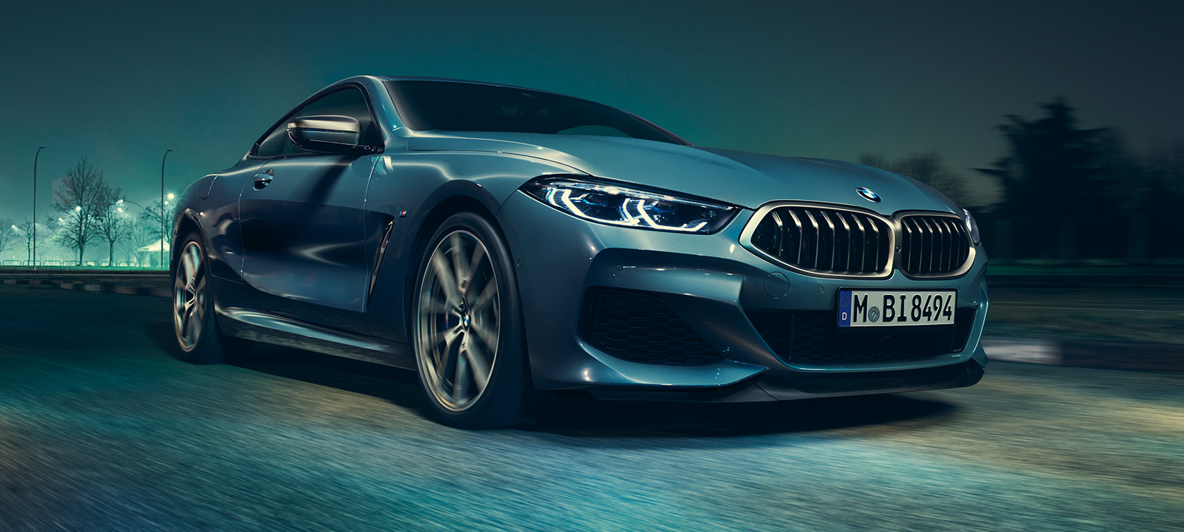 BMW M850i xDrive Купе, три четвърти изглед отпред. BMW M850i xDrive Купе в цвят Barcelona Blue metallic в движение, три четвърти изглед отпред.