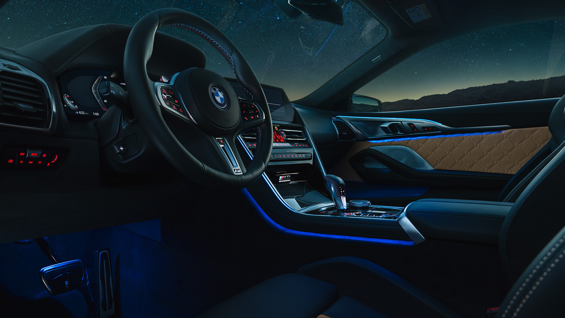 BMW M8 Competition Купе, кокпит. BMW M8 Competition Купе, кокпит през нощта с М кожен волан и синьо вътрешно осветление.