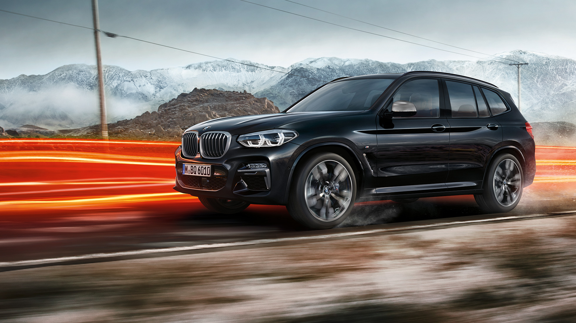BMW X3 M40i и BMW X3 M40d, страничен изглед. BMW X3 M40i и BMW X3 M40d в цвят Black Sapphire metallic, в движение, екстериор, страничен изглед на фона на планински пейзаж със светлинни ивици.
