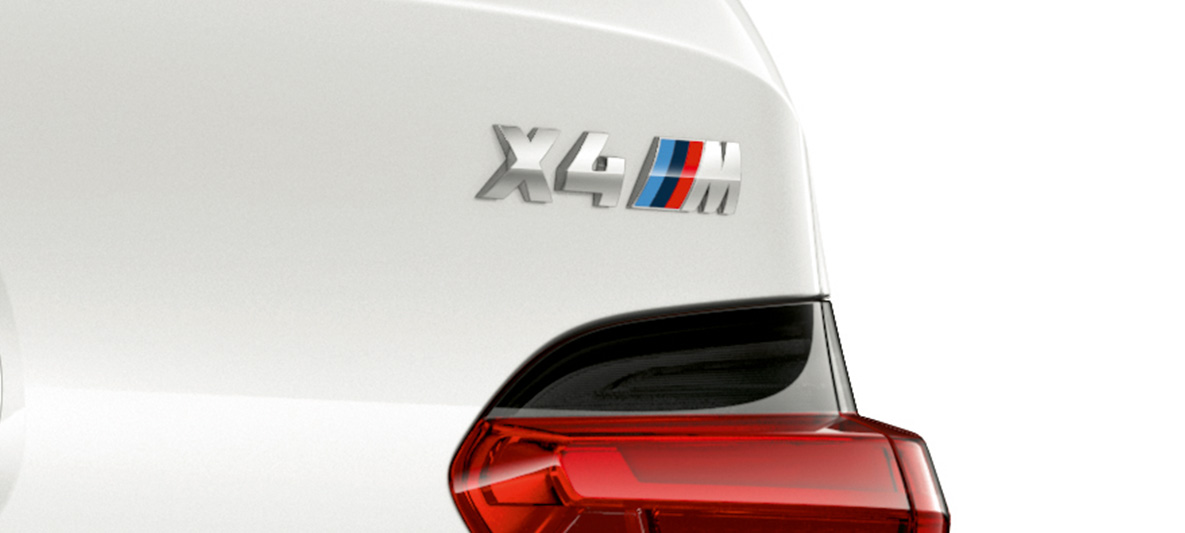 BMW X4 M, означение на модела. BMW X3 M в цвят Alpine White, екстериор, снимка отблизо на задната част с означение на модела.