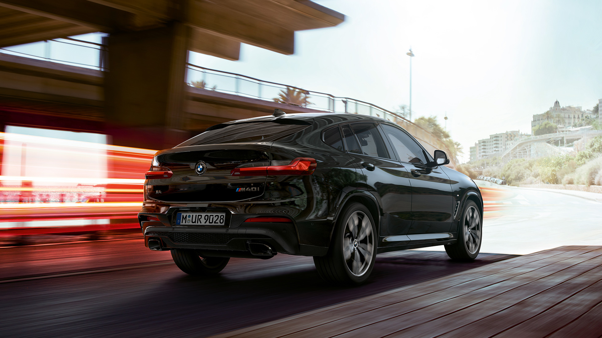 BMW X4 M40i, три четвърти изглед отпред. BMW X4 M40i в цвят Black Sapphire metallic, в движение, екстериор, три четвърти изглед отпред със светлинни ивици.