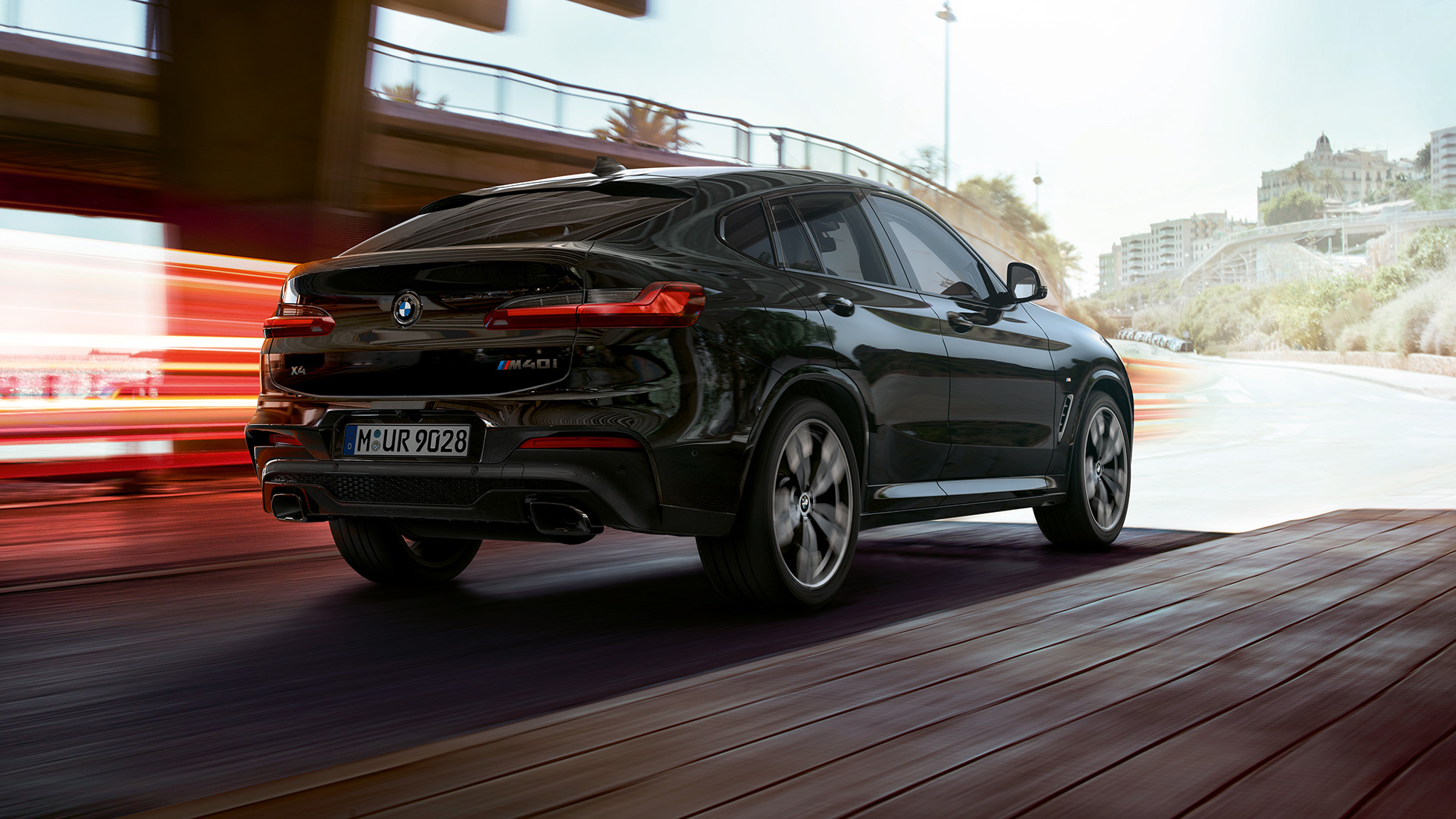 BMW X4 M40i и BMW X4 M40d, три четвърти изглед отпред. BMW X4 M40i и BMW X4 M40d в цвят Black Sapphire metallic, екстериор, три четвърти изглед отпред отдясно със светлинни ивици.