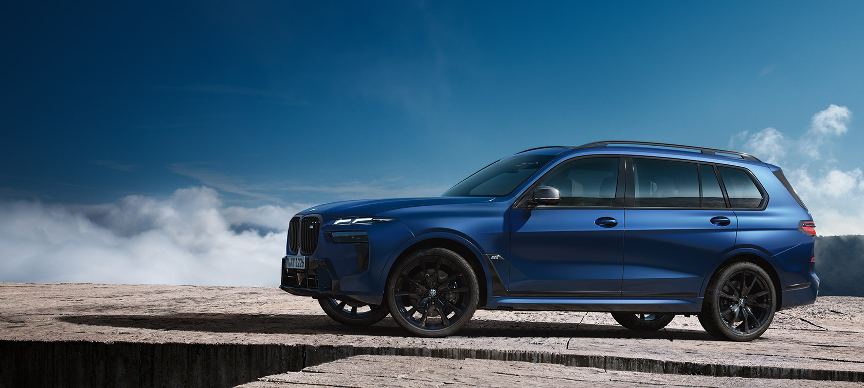 BWM X7 M60i xDrive G07 LCI Frozen Marina Bay Blue страничен изглед пред планински пейзаж