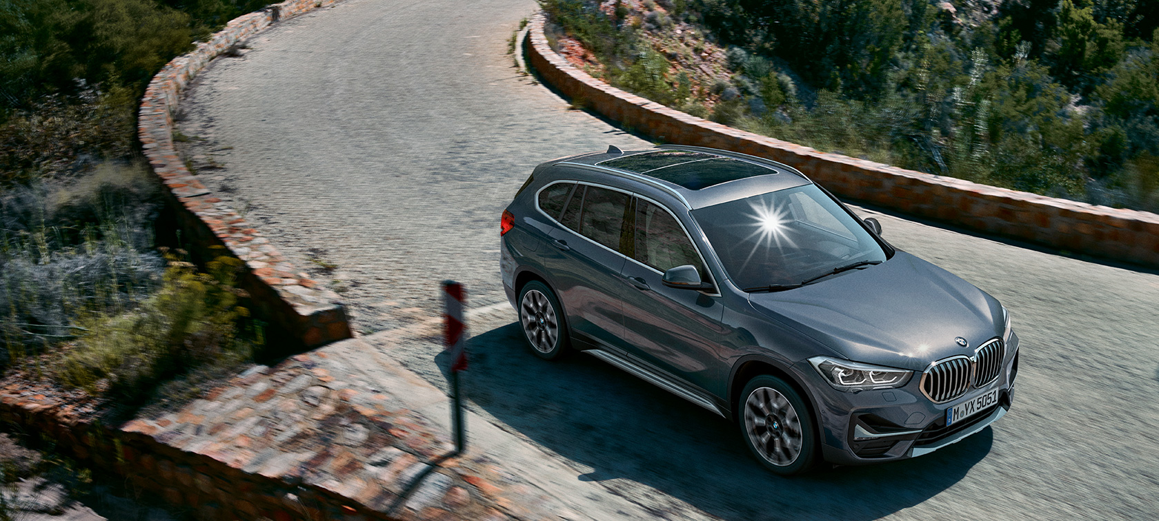 BMW X1, три четвърти изглед отпред. BMW X1, три четвърти изглед отпред, в движение на фона на планински пейзаж.