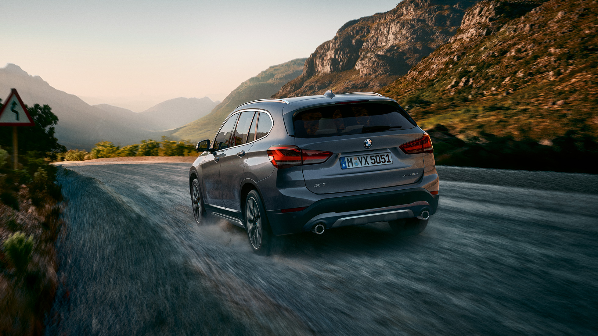 BMW X1, три четвърти снимка отзад BMW X1, три четвърти снимка отзад в движение на фона на планински пейзаж.