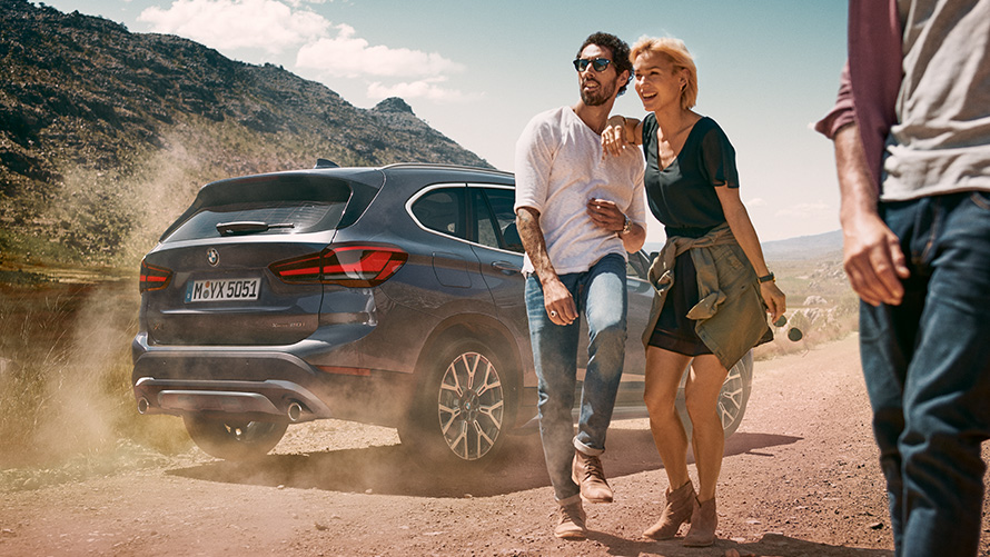 BMW X1 F48 LCI Storm Bay три четвърти изглед отзад BMW X1 F48 LCI Storm Bay три четвърти изглед отзад в покой с хора пред него