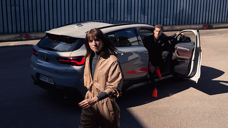 BMW X2 F39 Brooklyn Grey три четвърти изглед отпред с отворена врата и двама пътника BMW X2 F39 Brooklyn Grey три четвърти изглед отпред с отворена врата и двама пътника
