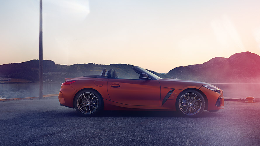 Оранжево BMW Z4 First Edition в покой в завой Оранжево BMW Z4 First Edition в покой в завой на фона на планински пейзаж
