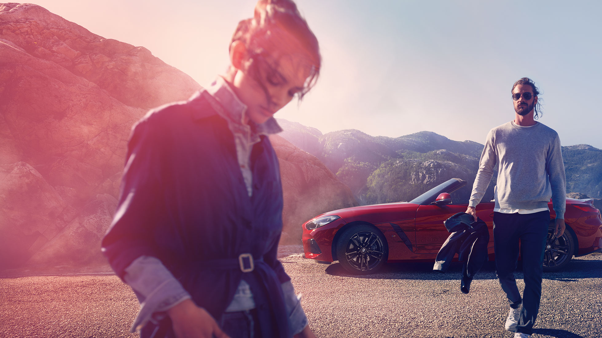BMW Z4 Роудстър на фона на планински пейзаж Мъж и жена пред BMW Z4 Роудстър на фона на планински пейзаж