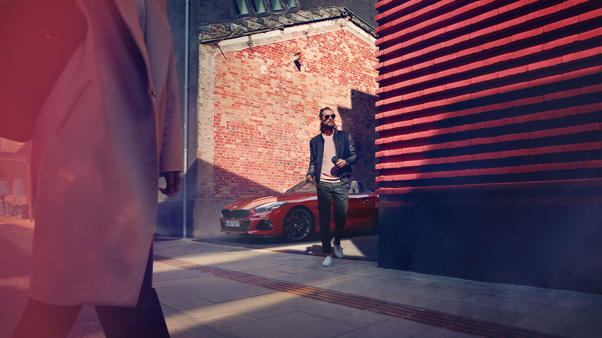BMW Z4 Роудстър в странична улица Мъж на странична улица пред BMW Z4 Роудстър