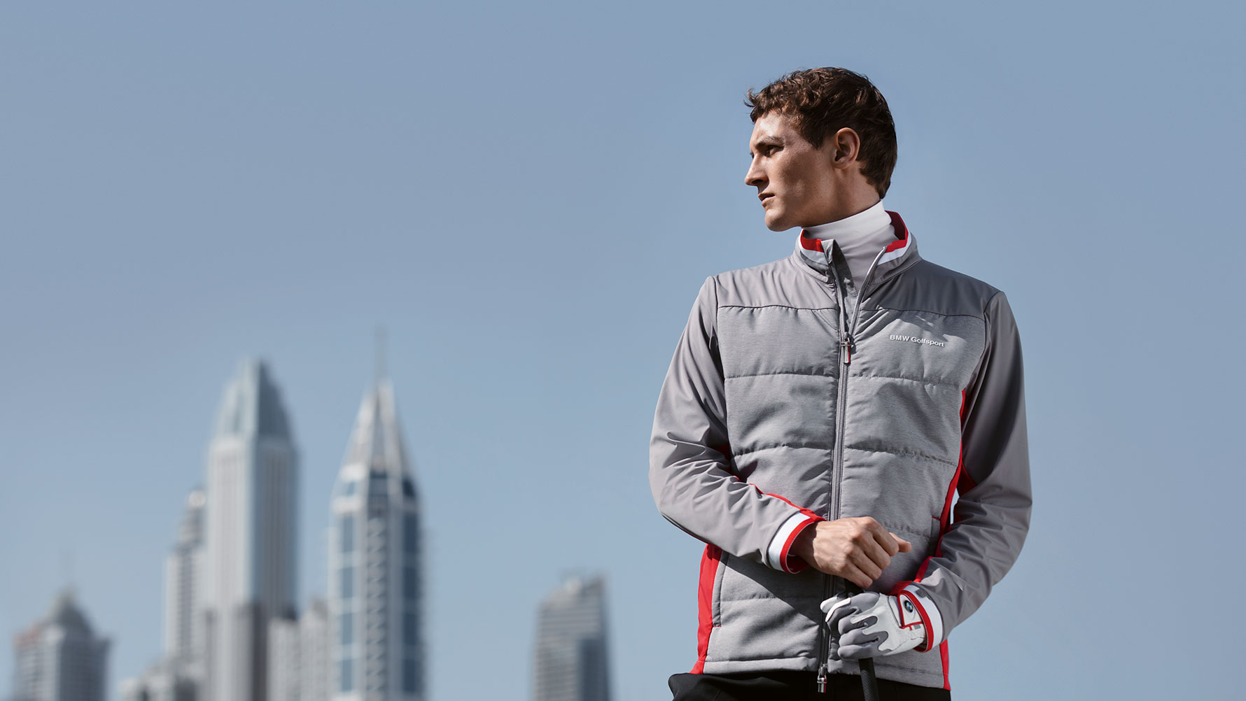 Ein Mann präsentiert Produkte der BMW Golfsport Collection vor der Skyline einer Großstadt. Ein Mann präsentiert Produkte der BMW Golfsport Collection vor der Skyline einer Großstadt.