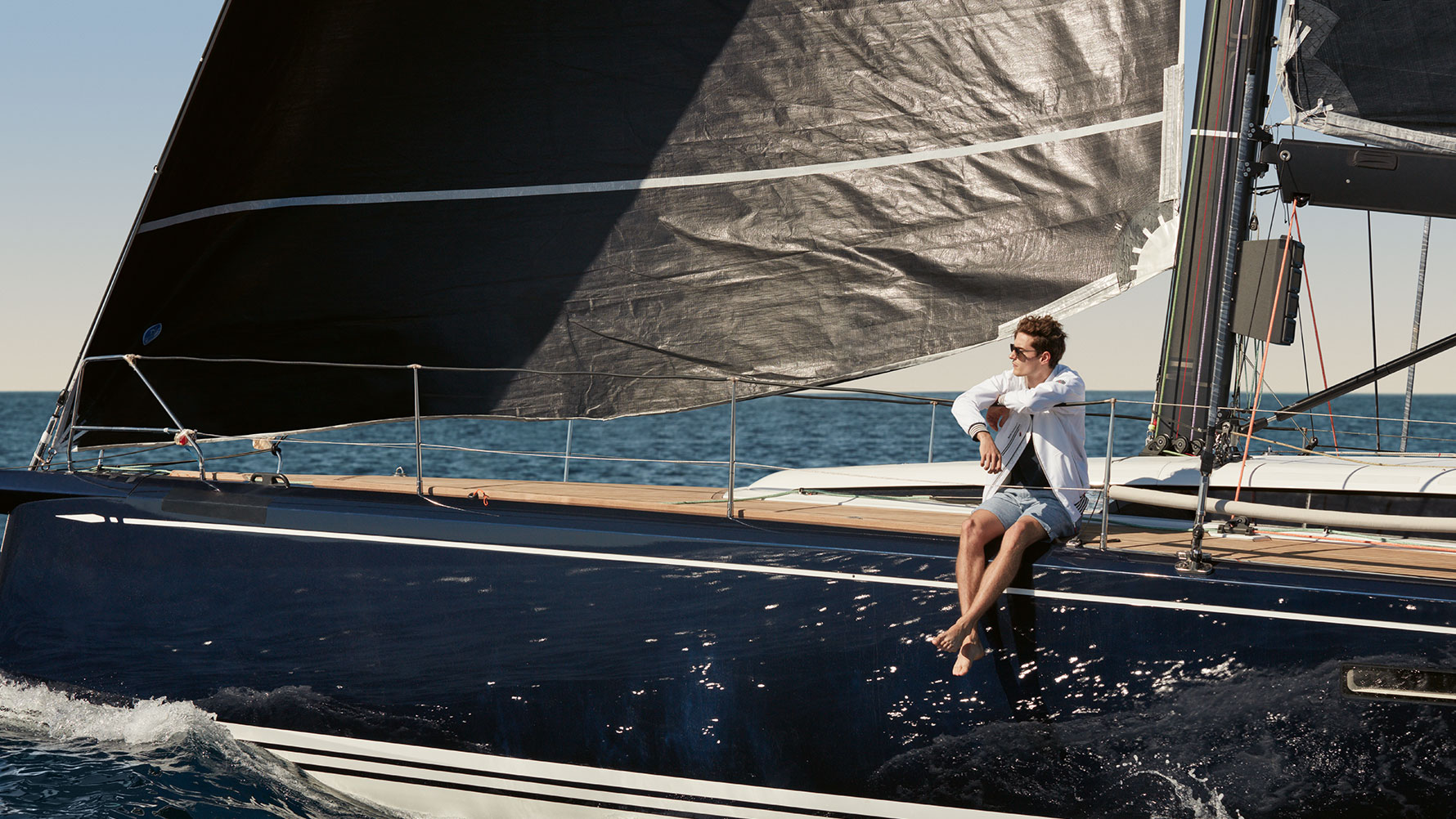 Mann sitzt mit BMW Yachtsport Jacke Herren aus der BMW Yachtsport Collection auf Segelyacht. Mann sitzt mit BMW Yachtsport Jacke Herren aus der BMW Yachtsport Collection auf Segelyacht.
