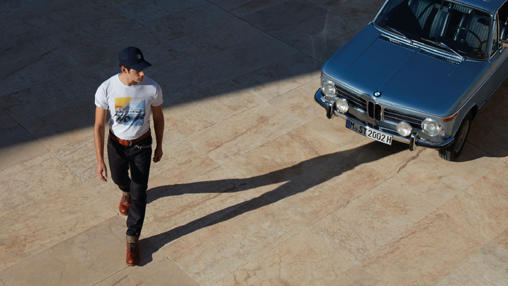 Mann trägt BMW Classic T-Shirt Herren aus der BMW Classic Collection und bewundert einen BMW Oldtimer. Mann trägt BMW Classic T-Shirt Herren aus der BMW Classic Collection und bewundert einen BMW Oldtimer.
