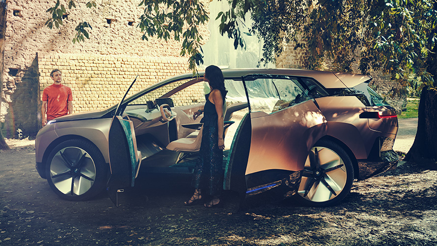 BMW Vision iNEXT отстрани BMW Vision iNEXT отстрани с жена до отворена врата и мъж на заден план