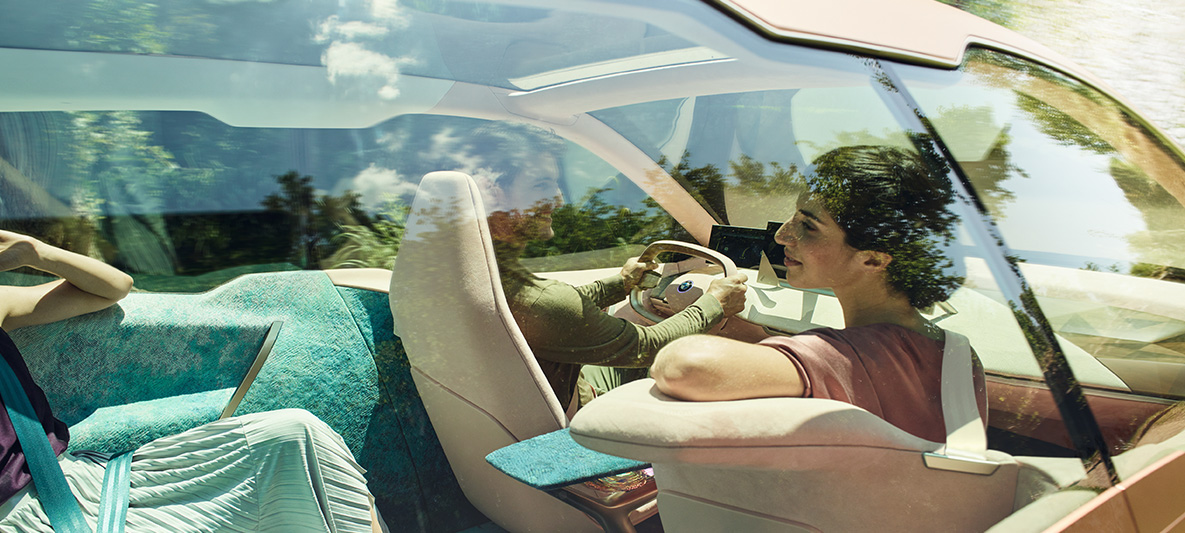 Жена на седалката до водача в BMW Vision iNEXT Жена с тъмна коса на седалката до водача в BMW Vision iNEXT се обръща към задните седалки